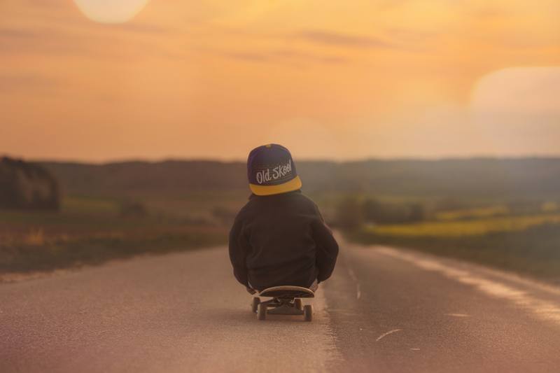 Junge auf Skateboard auf einer Landstraße – der Start in die Mobilität